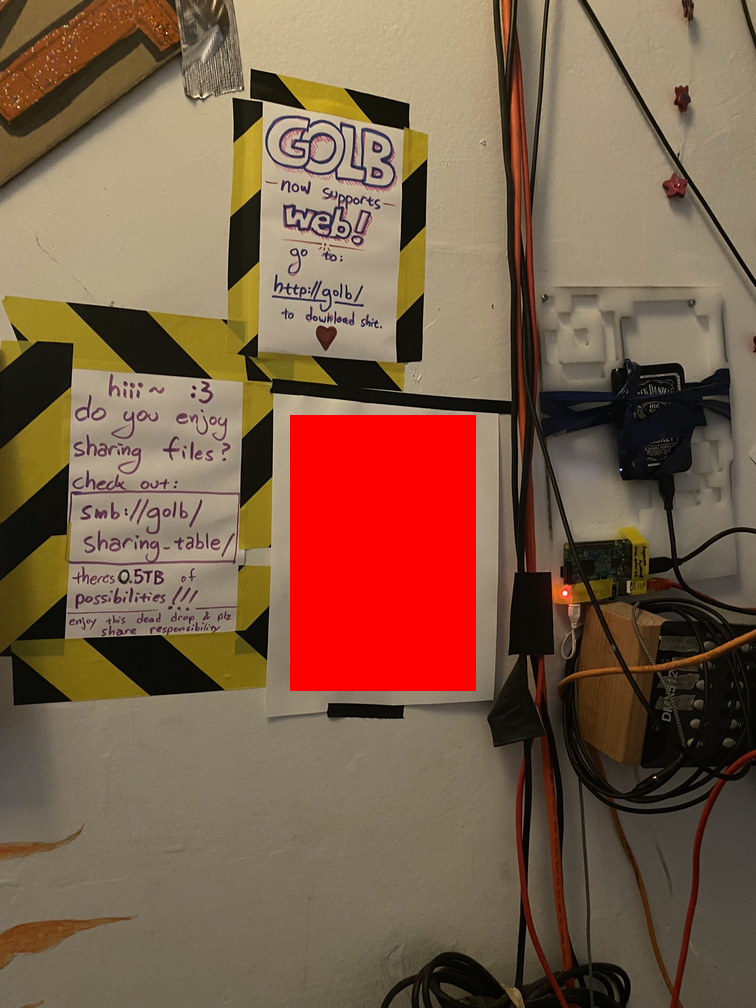 A Raspberry Pi attached to a Jack Daniels hard drive, hung on a wall and accompanied by posters